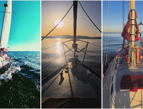 Un velero navegando en un mar tranquilo, bajo un cielo teñido de rojo y naranja por el atardecer.