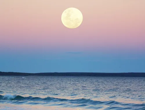 Full Moon even with light, sky degraded in shades of blue, purple, gold, pink, yellow. Calm sea.