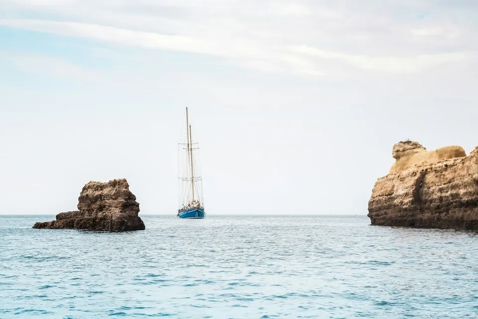 A boat between rock formations on the Algarve coast. Photo via Unsplash