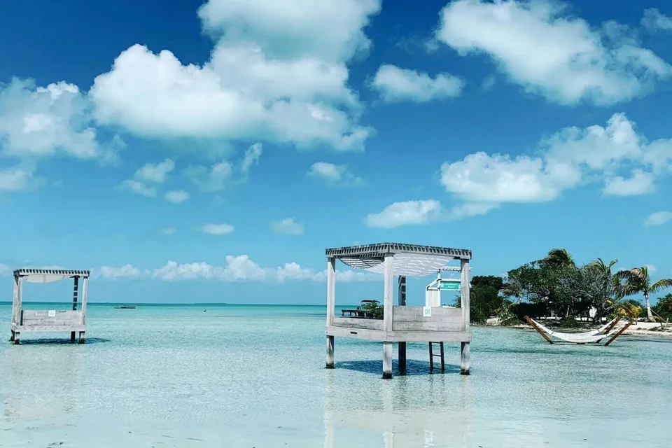 A wooden gazebo over turquoise water in Belize. Photo via Unsplash