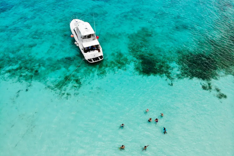 A boat anchored in clear turquoise water, Cozumel. Photo via Unsplash