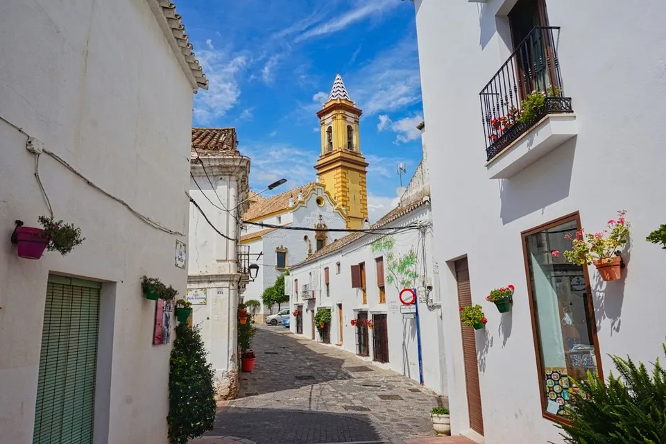 A street with a clock tower in Estepona old town. Photo via Unsplash