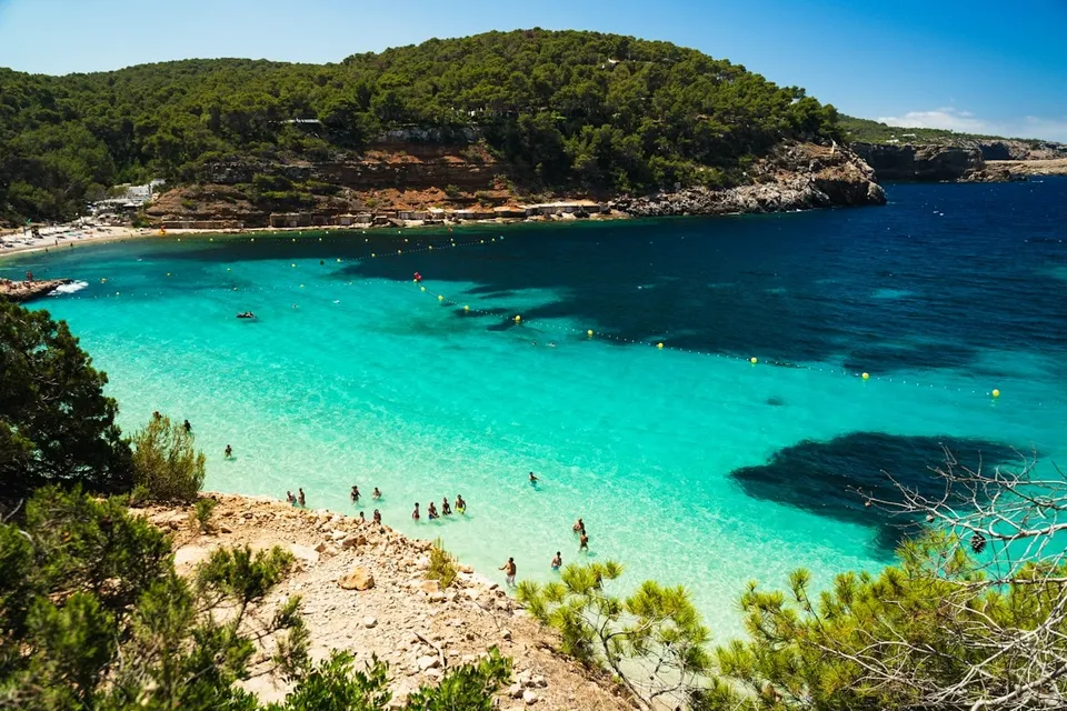 Swimmers in a turquoise cove in Ibiza. Photo via Unsplash