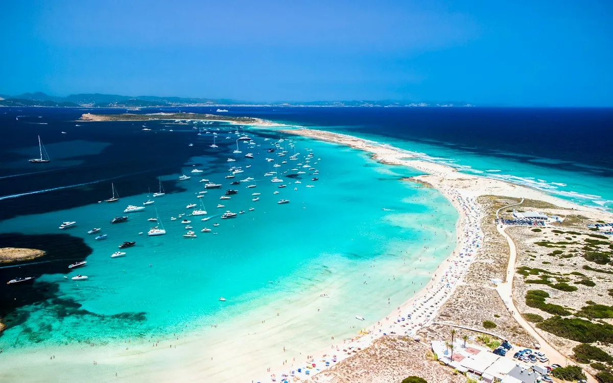 Boats anchored in turquoise water off a white-sand beach