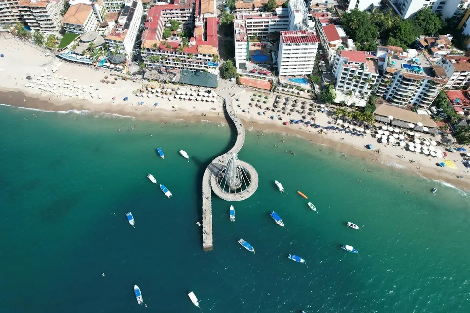 Aerial view of a pier and boats on a beach in Puerto Vallarta. Photo via Unsplash