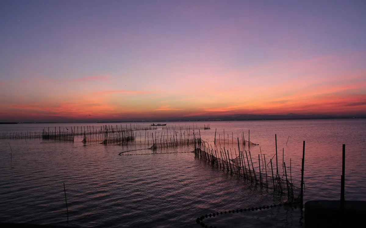 Sunset over a lagoon near Valencia with fishing stakes