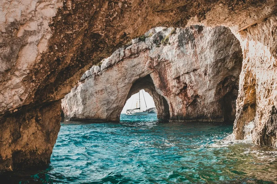 A sailboat seen through an arch of the Blue Caves, Zakynthos. Photo via Unsplash