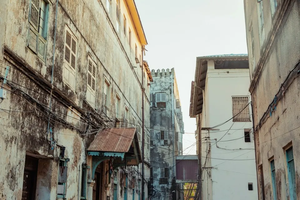 A narrow alley with a clock tower in Stone Town, Zanzibar. Photo via Unsplash