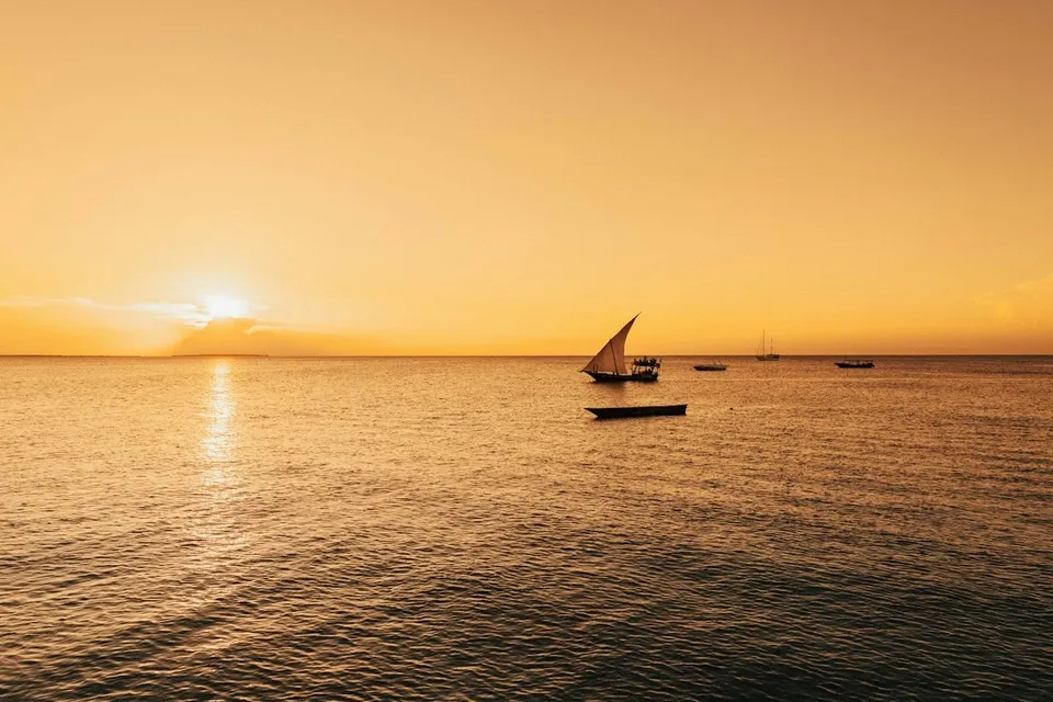 A traditional dhow sailing at sunset off Zanzibar. Photo via Unsplash